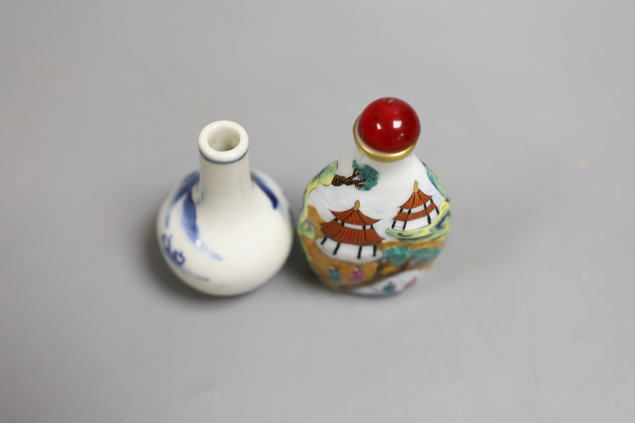Two Chinese snuff bottles, to include a blue and white c.1900 bottle, and a famille rose bottle with stopper, largest 8.5cm long, (2)